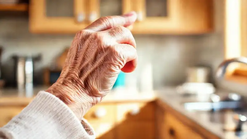 Una anciana agarra con seguridad en cocina